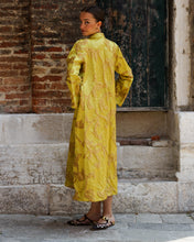Load image into Gallery viewer, Woman in a yellow coat standing against a brick wall.