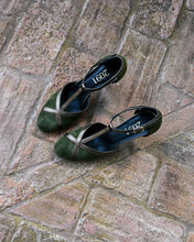 Load image into Gallery viewer, A pair of dark green suede slingback flats with metallic silver crisscross straps, displayed on a rustic stone brick surface. The brand name '2091' is printed in gold on the insole.

